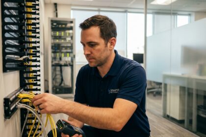 Technicien IT connectant des câbles téléphoniques dans un panneau de brassage en entreprise